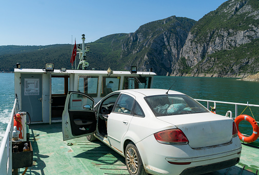 man traveling by car ferry sitting in the car using a mobile phone. 
To go to Şahinkaya Canyon, located on the Kızılırmak River, you can travel by car ferry. Taken with a full-frame camera in sunny weather.