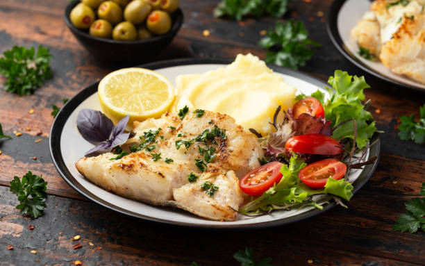 istock Fried cod loin fillet with mashed potato and vegetable salad served with fresh lemon 1401177657