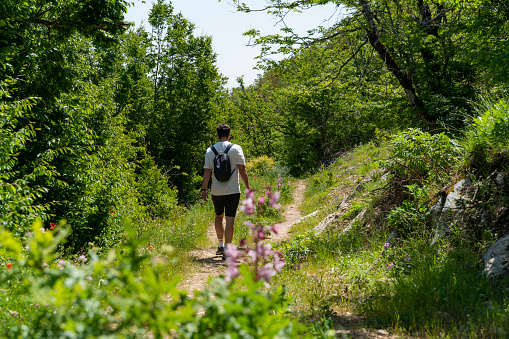 Man trekking in the Beaver Forests in Vezirköprü, Black Sea Region, Samsun Province. The image of the man walking on the path stretching between the flowers blooming in spring and the trees with fresh green leaves was shot with a full frame camera.