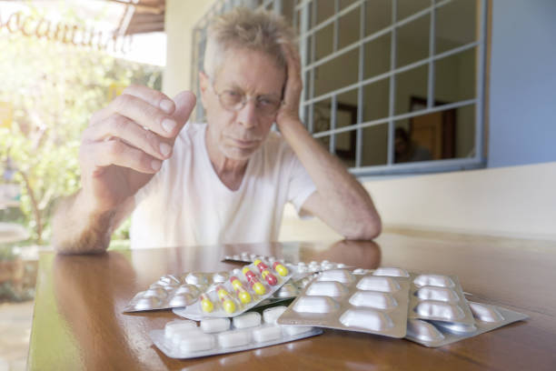Close-up of Man Holding Medicines. Multiple Prescribed Medicines on the Table.