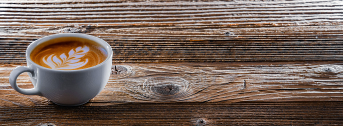 A cup of coffee on an old wooden table.