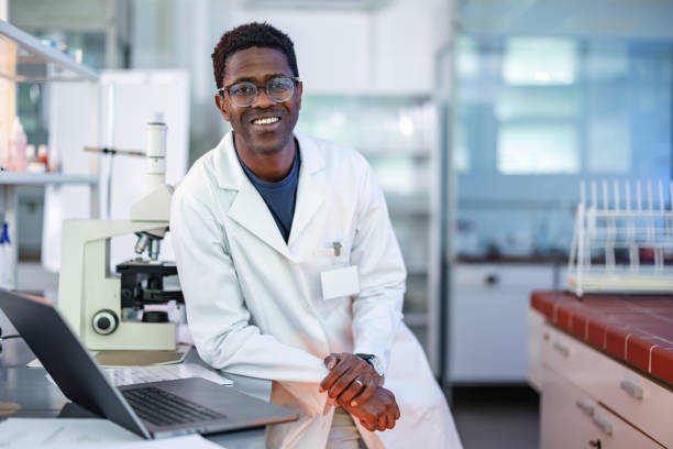 молодой афроамериканский ученый, стоящий в лаборатории - scientist chemist doctor lab coat стоковые фото и изображения