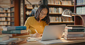 istock Young lady using a laptop to do research on the internet. Woman working on a project. Mixed race woman sending emails. 1401178943