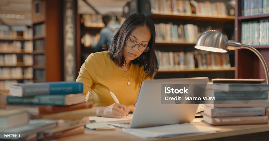 Young lady using a laptop to do research on the internet. Woman working on a project. Mixed race woman sending emails. Learning Stock Photo
