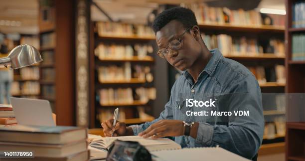 African Man Sitting Inside A Library Alone Doing Research Man Working On A Project Young Man Doing Research For A Case Lawyer Working On A Case Stock Photo - Download Image Now