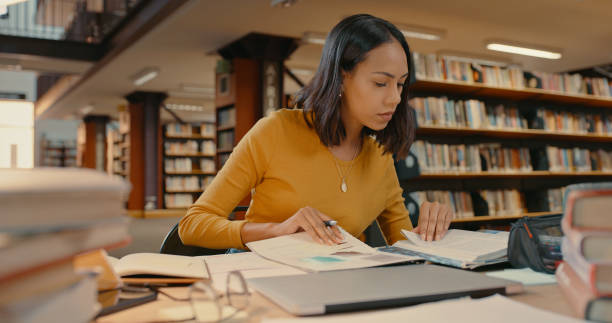 prawniczka pracująca nad sprawą w bibliotece sama. kobieta prowadząca badania. kobieta mieszanej rasy pisząca swój projekt - male education college student nerd zdjęcia i obrazy z banku zdjęć