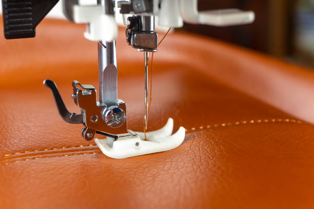 istock Modern sewing machine presser foot with a needle sews brown leather 1401179952