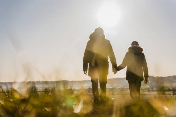 istock Father with son holding hands together while walking on meadow 1401180180