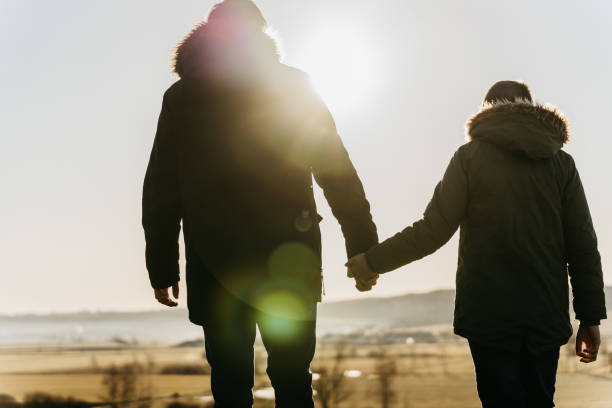 istock Father with son holding hands together while walking in field 1401180234