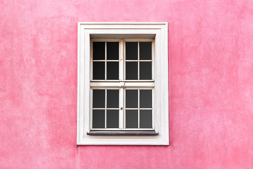 Renaissance style window with white frame on pink wall color. Building exterior