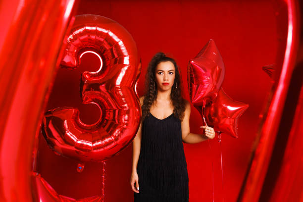 istock Funny girl with red balloons on a red background. Young 1401181569