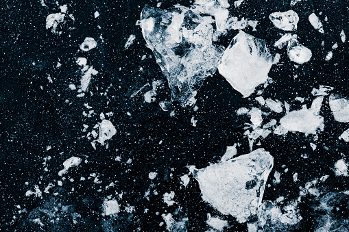 Ice, crushed on black background. Pieces of crushed ice spread away. Crushing of the ice.