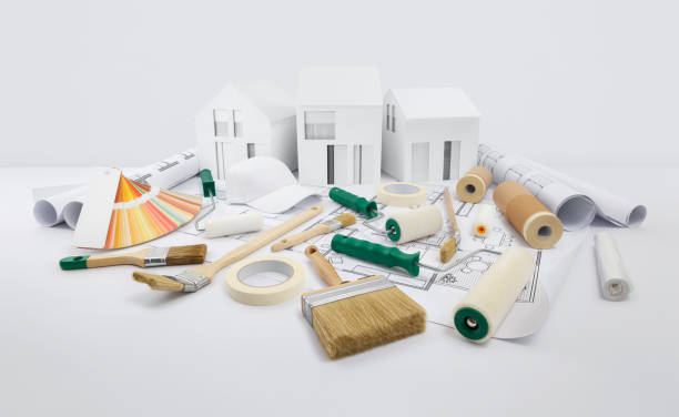house painter tools, brushes, paint rollers, paper masking tape and colors swatches on blueprint with model house, supply and service in color shop in the hardware and store of building material. herramientas de pintor de casas, pinceles, rodillos de pintura, cinta adhesiva de papel y muestras de colores en el plano con modelo de casa, suministro y servicio en la tienda de color en la ferretería y tienda de material de construcción.