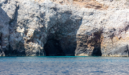Cave and cliff, Aegean Sea. Cyclades Greece. Rock coast, turquoise water. Seascape near Ios island