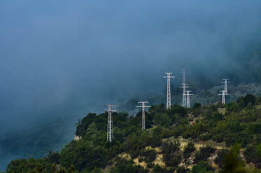 High voltage power transmission towers in fog on mountain