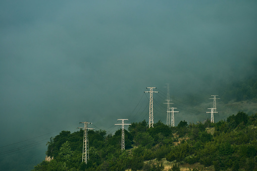 High voltage power transmission towers in fog on mountain