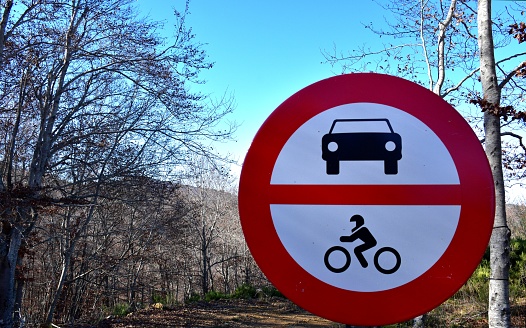 Prohibition sign to cars and motorcycles on forest track in beech forest.