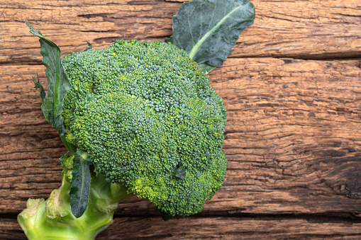 Whole broccoli vegetable on wood, top view, healthy eating clean food concept.