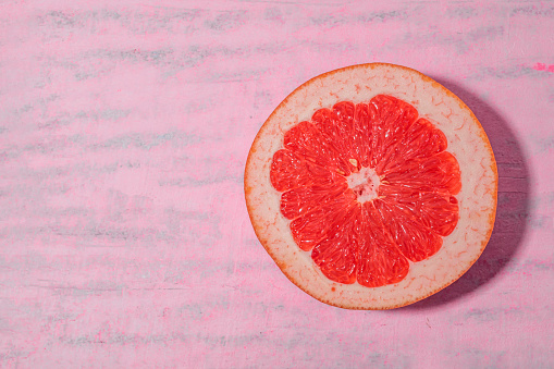 Grapefruit on watercolor pink background, top view, healthy fruit food concept.