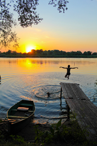 The photo was taken in Ukraine, on a river called the Southern Bug. The picture shows children swimming in the river at sunset.