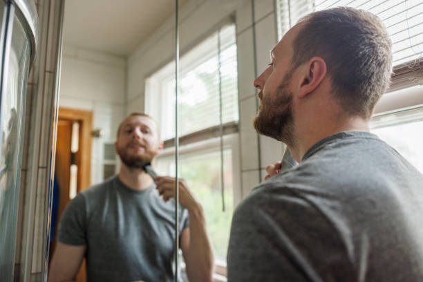 istock Caucasian White man is trimming his beard using a portable cordless trimmer in a modern bathroom. 1401193465