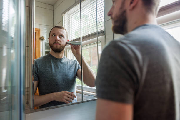 istock Caucasian White man using a portable cordless trimmer to remove ears' hairs in a modern contemporary bathroom. 1401193470