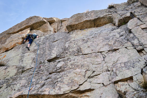 istock Man climbing up a vertical rock wall. 1401198140