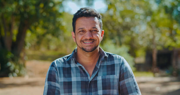 portrait of young man in the casual shirt in the farm on the colorful sky background. - shirt lifestyles close up cheerful imagens e fotografias de stock