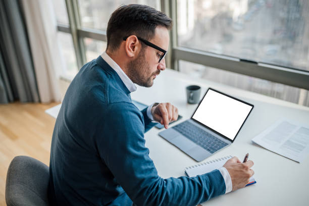 istock High angle view of serious businessman making notes while sitting at office desk 1401199658
