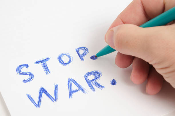 istock Hand with ballpoint pen and inscription stop war white background. 1401202204