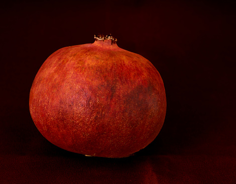 red pomegranate and banana lie on a black background