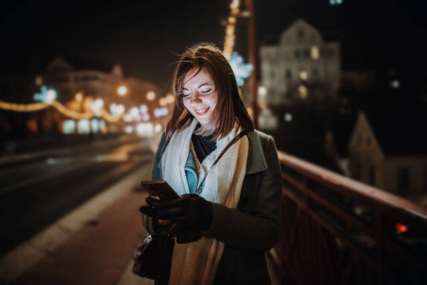 istock Woman text messaging using mobile phone outdoors in city at night 1401204680