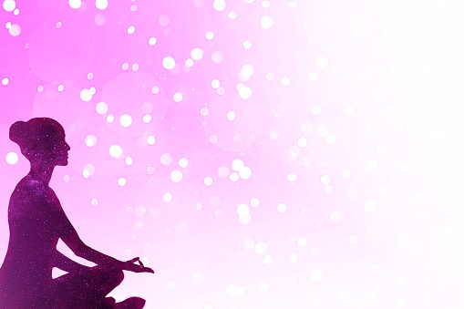 Cosmos silhouette of a woman meditating over bokeh pink background