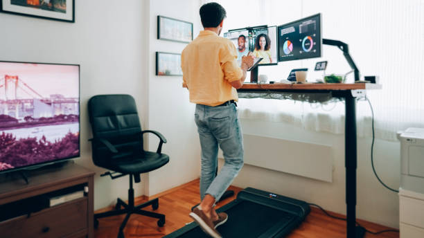 istock Man at standing desk home office talking on business video call 1401205587