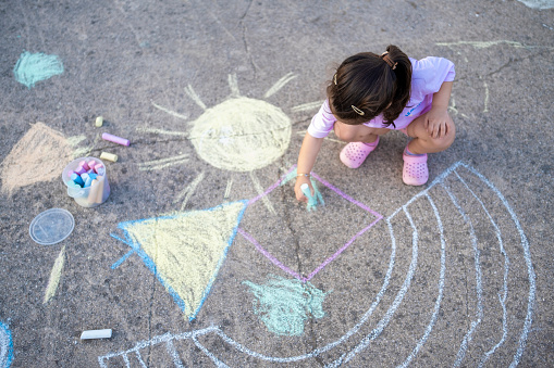 child's hand draws hearts, draws with chalk on the pavement. selective focus