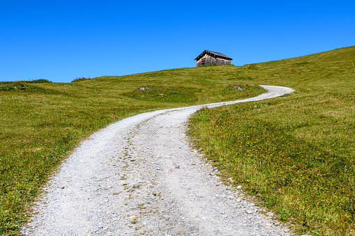 Curvy mountain road to the old hut on top of the hill