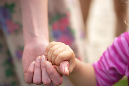 Close-up of child holding mom's hand, sand on hands after playing in park