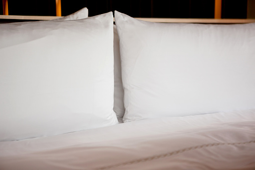 Pillows arranged on bed, all white bedding, copy space