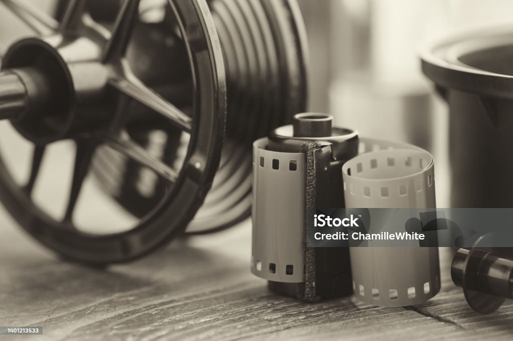 Photo film roll and cassette, photographic equipment - developing tank with its film reels on background. Selective focus. Retro black and white photo. Photography Stock Photo
