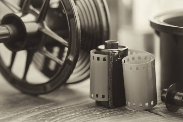 Photo film roll and cassette, photographic equipment - developing tank with its film reels on background. Selective focus. Retro black and white photo. Photo film roll and cassette, photographic equipment - developing tank with its film reels on background. Selective focus. Retro black and white photo. spool photos stock pictures, royalty-free photos & images