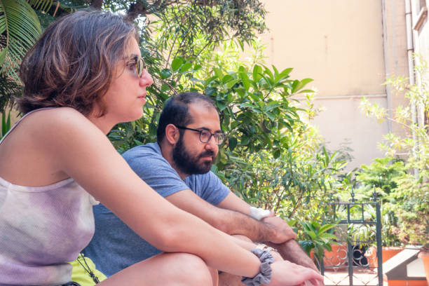 um jovem, uma jovem e um menino estão sentados nos degraus da rua em um dia ensolarado de verão. - staircase steps istanbul turkey - fotografias e filmes do acervo