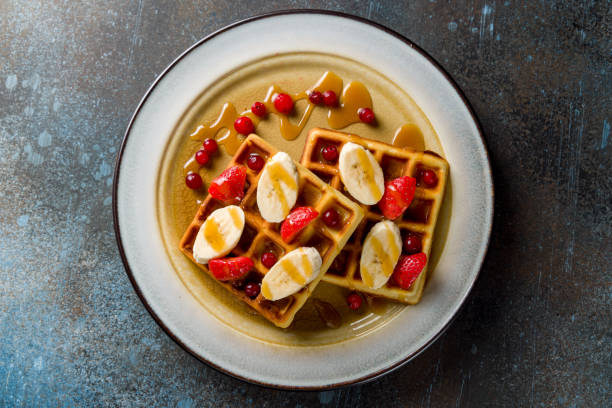 istock waffles with fresh strawberries, bananas and powdered sugar on blue stone table 1401215590