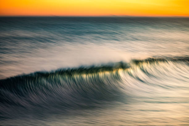 istock Smooth golden ocean wave forming during a golden sunrise at the beach 1401217721