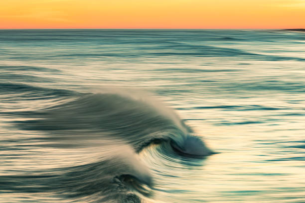 istock Smooth golden ocean wave breaking during a dramatic sunrise at the beach 1401218032