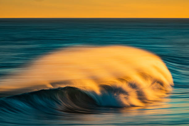 istock Smooth golden ocean wave breaking during a dramatic sunrise at the beach 1401218058