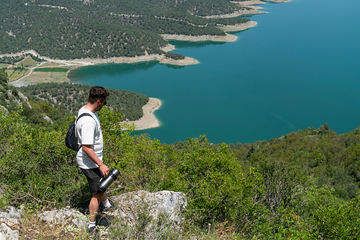 Man trekking in the view of Kızılırmak River in the canyon in Vezürköprü, Samsun province, Black Sea Region. \nThe view of the Kızılırmak River can be seen from the summit of the mountain. The wooded area was shot with a full frame camera in sunny weather.