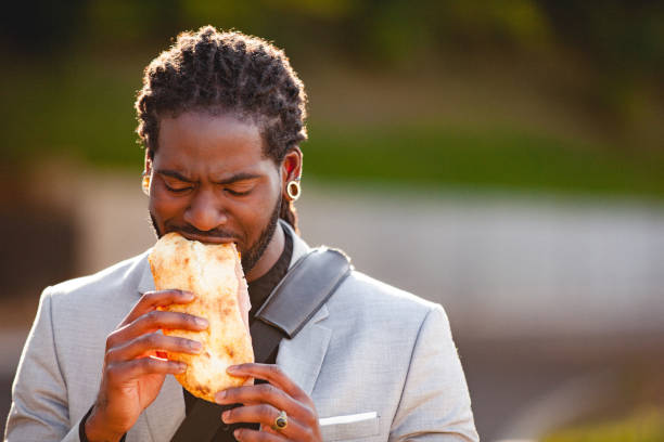 Portrait of a young handsome man eating a sandwich stock photo