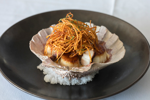 Clams in a clam shell bowl with crispy asian noodles on rice in Chatham, Massachusetts, United States