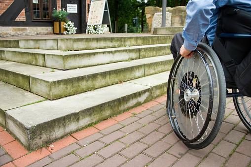 Man in wheelchair in front of unsurmountable steps of staircase