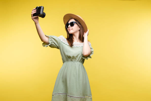 istock Happy traveler woman posing making selfie using camera isolated at yellow studio background 1401239437